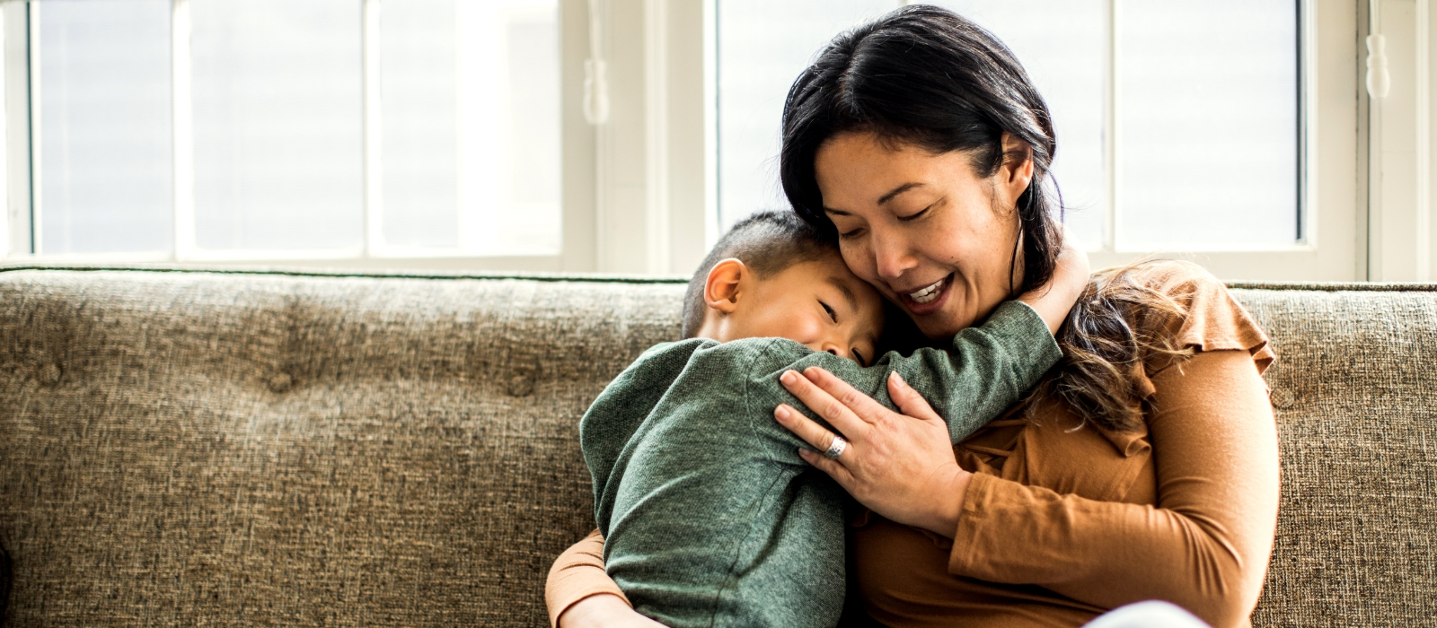 Mother and child sharing a warm embrace on a couch.